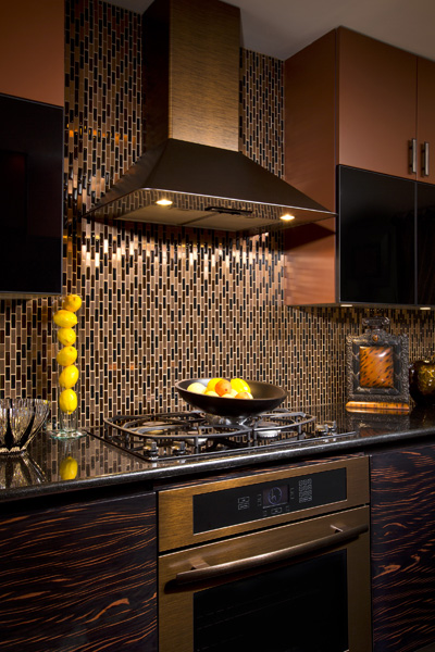 A richly colored, but stark chimney hood was called for in this urban kitchen to balance the patterns of the metal tilework and exotic cabinetry. By Teakwood Builders, kitchen and bath remodeler, custom home builder and general contractor Saratoga Springs and Capital Region.