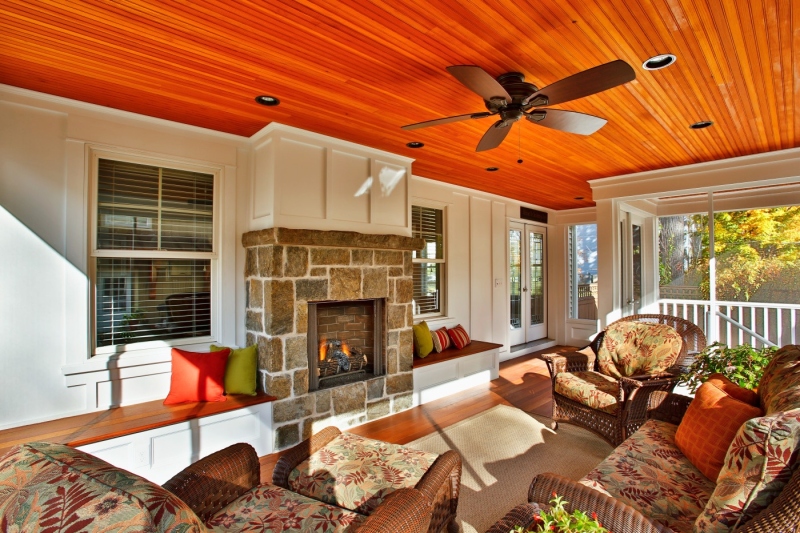 A stone surround and board and batten upper mantle makes the fireplace an attractive center of attention for this screened porch.