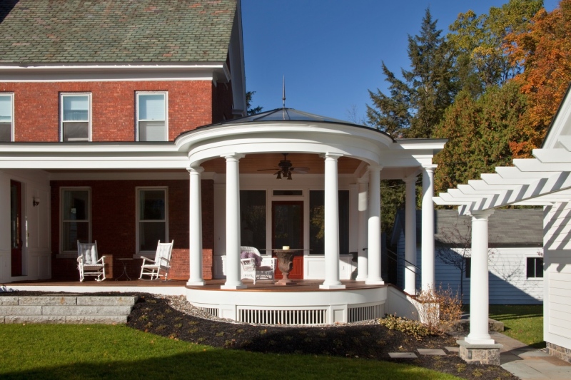 Teakwood Builders worked with a local architect to design this extensive porch addition to an 1873 residence, featuring an alfresco dining rotunda. Tuscan columns provide structural support and also echo the existing home’s architectural details. A new pergola links the addition at the home’s rear to the newly constructed carriage house-style garage.