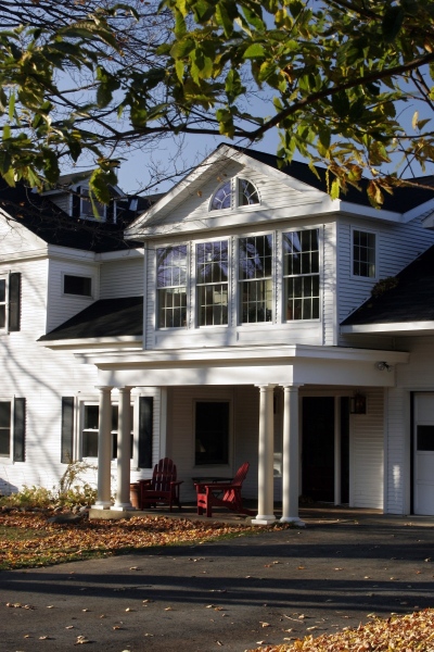 Teakwood balanced the scale and emphasized the more useful entrance by adding a Greek Revival porch with an open portico, a wall of Palladian windows and twin support columns.