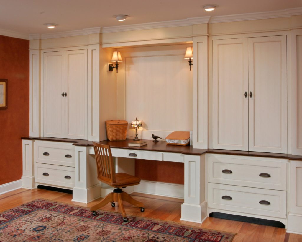 Teakwood designed and built this ample unit to serve as an attractive home office between the kitchen and great room. Deep drawers contain files, while upper cabinets conceal books and media components. Detailed millwork and furniture-like details help to integrate this unit into the nearby living spaces.