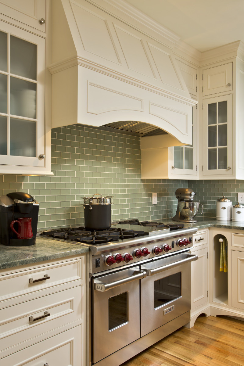 To avoid overpowering this cozier kitchen, Teakwood created elegant, unobtrusive millwork to hide the massive fan and 10-inch ductwork venting this two-bay, dual-fuel Wolf oven. By Teakwood Builders, kitchen and bath remodeler, custom home builder and general contractor Saratoga Springs and Capital Region .