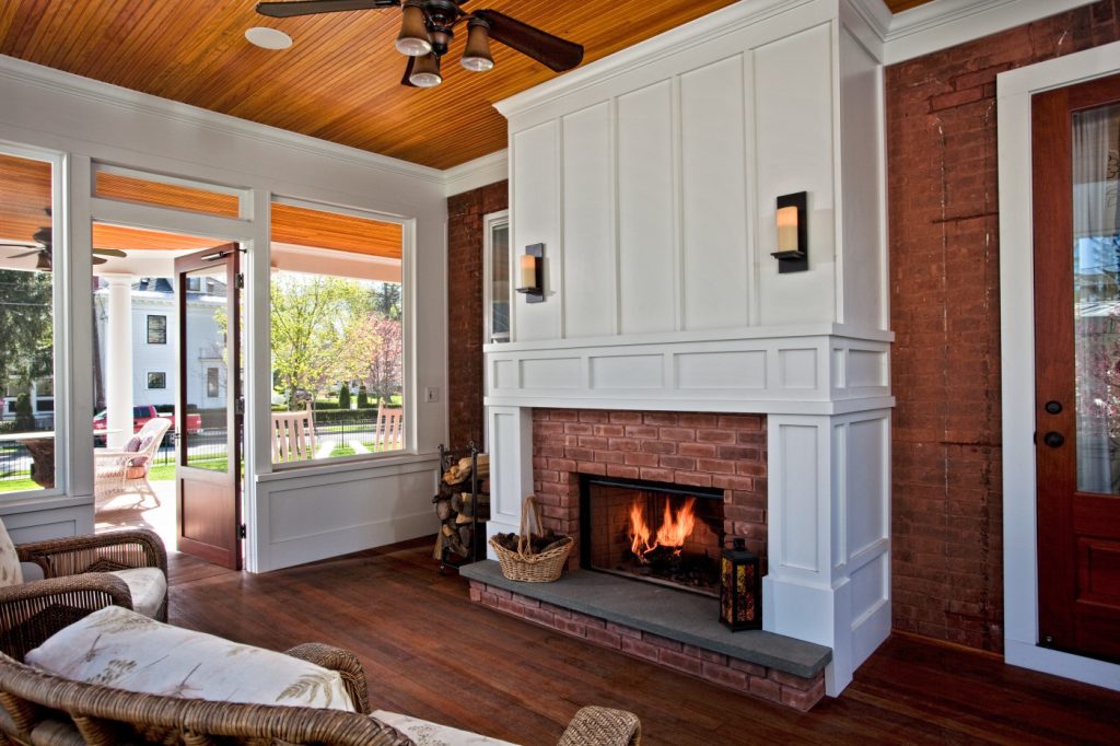 Rich, natural materials and finishes help this sitting porch fireplace comfortably maintain the character of this historic home year round. Teakwood Builders, kitchen and bath remodeler, custom home builder and general contractor Saratoga Springs and Capital Region
