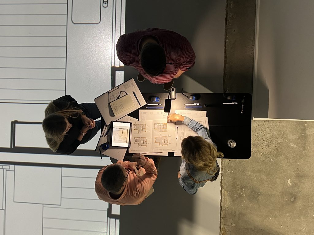 the design team and clients gather to discuss drawings